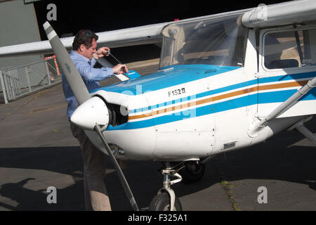 Aviazione generale un pilota di controllo dell'olio nel motore di un Cessna 152 come parte del pre volo controllo di ispezione nel Regno Unito Foto Stock