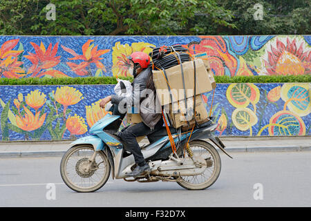 Ciclomotori e motocicli sono ovunque in Hanoi, Vietnam. Non è raro vedere enormi carichi su uno scooter. Foto Stock