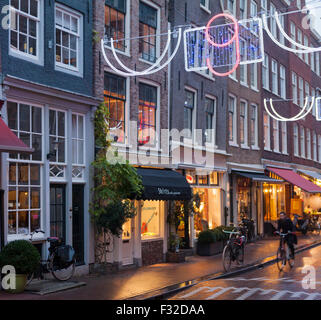 Ciclista al tramonto su Runstraat nel quartiere alla moda di nove strade dello shopping, Amsterdam Foto Stock