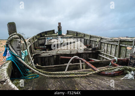 Abbandonata la pesca in barca da sinistra a rot e degrado sulla spiaggia di Dungeness, Kent. Un grigio, moody sky aggiunge alla triste scena Foto Stock