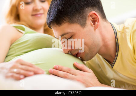 Futuro papà baciando la pancia di sua moglie incinta Foto Stock