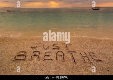 Nella foto una spiaggia al tramonto con le parole sulla sabbia 'appena respirare". Foto Stock