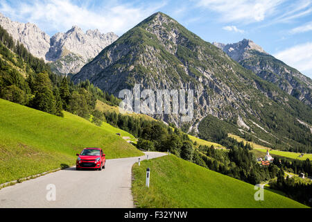 Auto rossa guida su strada alpina, Gramais, Austriaco Foto Stock