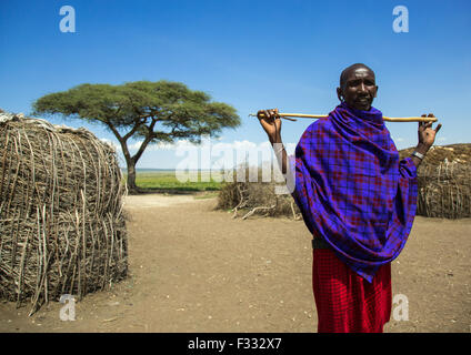 Tanzania, Regione di Arusha, Ngorongoro Conservation Area, uomo Masai con un bastone fuori casa Foto Stock