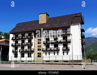 Casa con balconi e camini sul tetto su uno sfondo di una collina con alberi Foto Stock