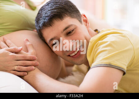 Il marito ascoltando la sua moglie del ventre Foto Stock