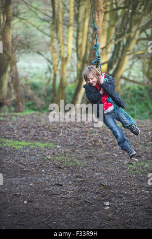 Ragazza che gioca su una corda swing in foresta NORFOLK REGNO UNITO Foto Stock