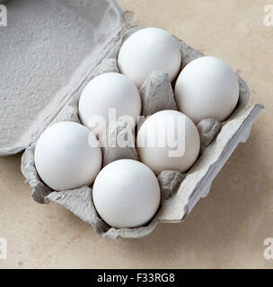 Sei uova di colore bianco in cartone sulla superficie di pietra Foto Stock