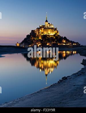 Una immagine a colori di riflessioni di Mont Saint Michel accesa fino al tramonto in una piscina di acqua sulla spiaggia al Mont Saint Michel Foto Stock