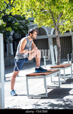 Bello atleta gamba facendo stretching su un banco di lavoro Foto Stock