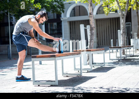 Bello atleta gamba facendo stretching su un banco di lavoro Foto Stock