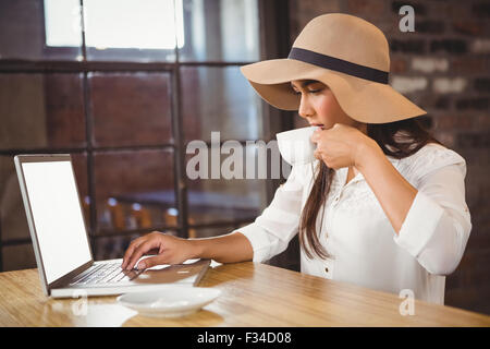 Una imprenditrice usando il suo computer portatile mentre si gusta un caffè Foto Stock