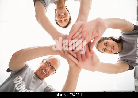 Volontari sorridente mettendo le mani insieme Foto Stock