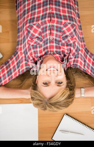 Donna sorridente giacente sul piano circondato da articoli per ufficio Foto Stock