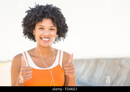 Giovane donna sportivo godersi musica e facendo del pollice in alto Foto Stock