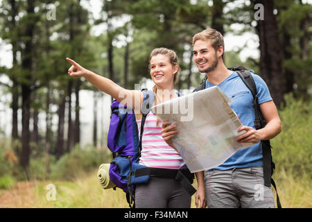 Giovani felici gli escursionisti il puntamento della distanza con una mappa Foto Stock