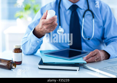 Immagine ritagliata del medico maschio holding pillola bottiglia in clinica Foto Stock