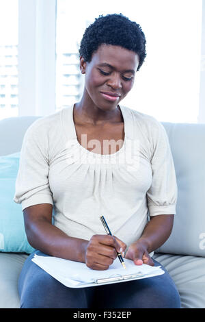 Donna incinta scrivere su blocco note Foto Stock