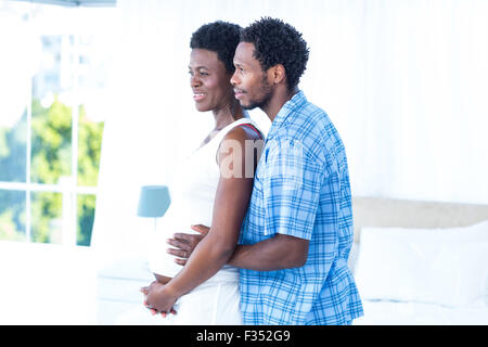 Il marito abbracciando la donna incinta Foto Stock