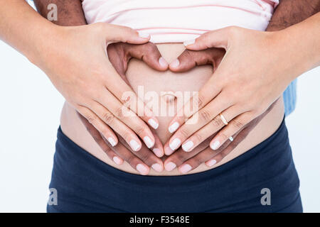 Sezione mediana delle mani messa a forma di cuore sulla pancia Foto Stock