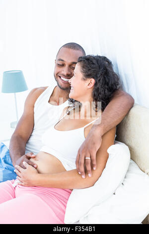 Donna incinta con il marito sdraiato sul letto Foto Stock