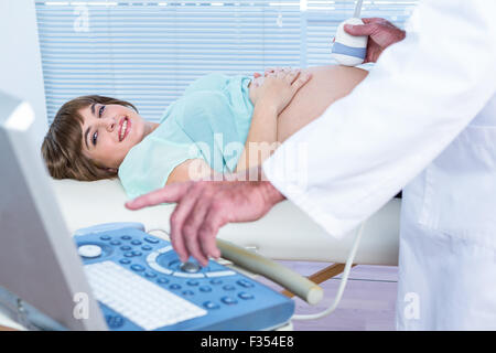 Medico che mostra il monitoraggio a ultrasuoni a felice donna in stato di gravidanza Foto Stock