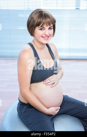 Ritratto di felice incinta Donna seduta sulla sfera di fitness Foto Stock