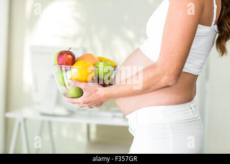 Vista laterale della donna azienda coppa di frutta Foto Stock