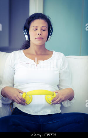 Donna seduta con gli occhi chiusi ascoltando musica Foto Stock