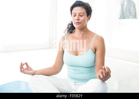 Donna incinta meditando nella posizione del loto Foto Stock