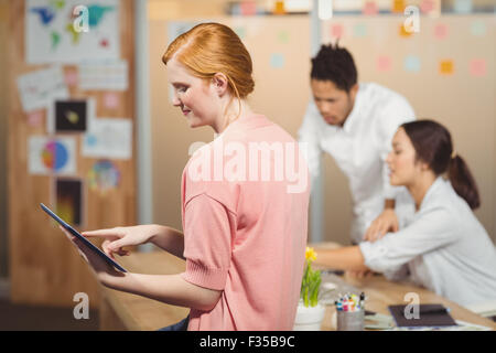 Imprenditrice utilizzando tavoletta digitale con i colleghi di lavoro in ufficio Foto Stock