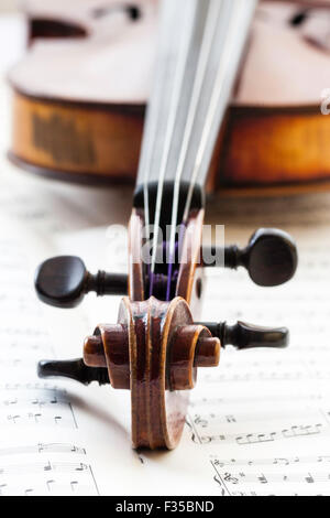 Un restaurato Thouvenel violino, Parigi 1800. La chiocciola, punture e piroli impostata su uno sfondo di musica del foglio nella luce naturale. Foto Stock