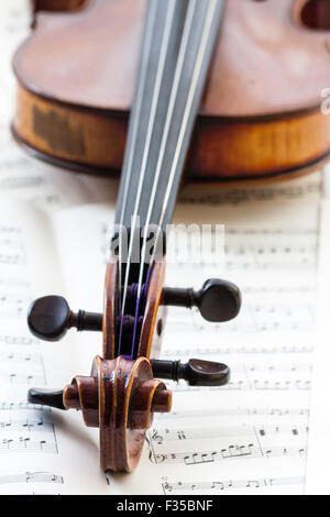 Un restaurato Thouvenel violino, Parigi 1800. La chiocciola, punture e piroli impostata su uno sfondo di musica del foglio nella luce naturale. Foto Stock