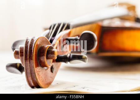 Un restaurato Thouvenel violino, Parigi 1800. La chiocciola, punture e piroli impostata su uno sfondo di musica del foglio nella luce naturale. Foto Stock