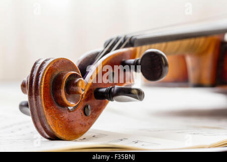 Un restaurato Thouvenel violino, Parigi 1800. La chiocciola, punture e piroli impostata su uno sfondo di musica del foglio nella luce naturale. Foto Stock