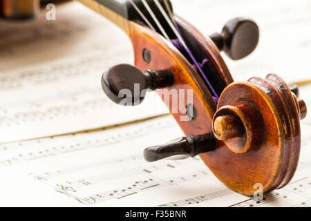 Un restaurato Thouvenel violino, Parigi 1800. La chiocciola, punture e piroli impostata su uno sfondo di musica del foglio nella luce naturale. Foto Stock