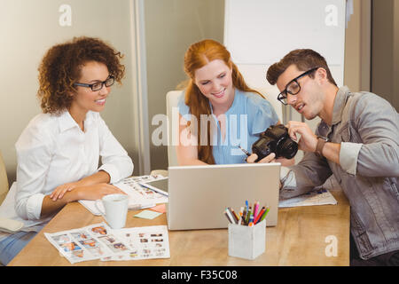 Imprenditore mostrando qualcosa sulla fotocamera per i colleghi di sesso femminile Foto Stock