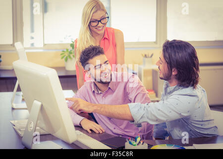 Imprenditore puntando sul computer come sorridere i colleghi lo sta guardando Foto Stock