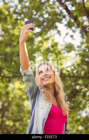 Basso angolo di visione della donna sorridente tenendo selfie Foto Stock
