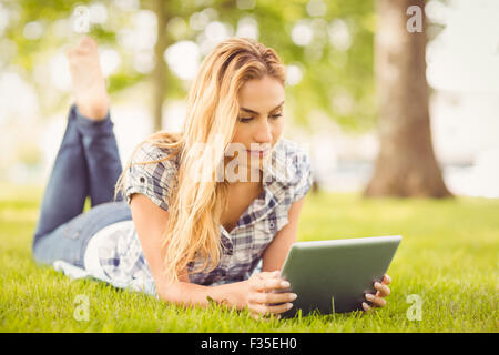 Donna che utilizza digitale compressa sdraiati sull'erba Foto Stock