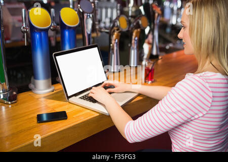Donna al lavoro su computer portatile al bancone bar Foto Stock