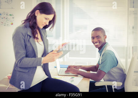 Ritratto di imprenditore sorridente lavorando sul computer portatile con la donna con tavoletta digitale Foto Stock