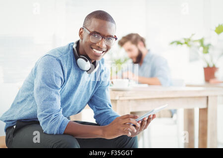 Ritratto di uomo sorridente con le cuffie mentre usando tavoletta digitale Foto Stock