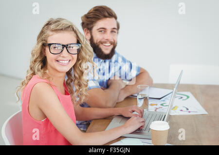 Ritratto di uomo sorridente e la donna utilizzando laptop alla scrivania Foto Stock