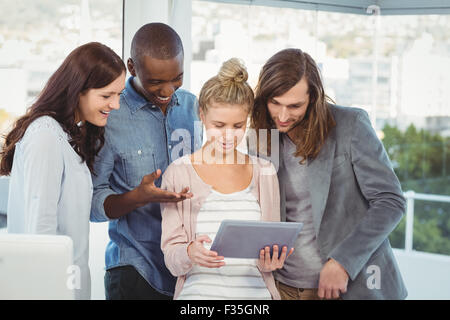Donna sorridente azienda digitale compressa e discutere con i colleghi in ufficio Foto Stock