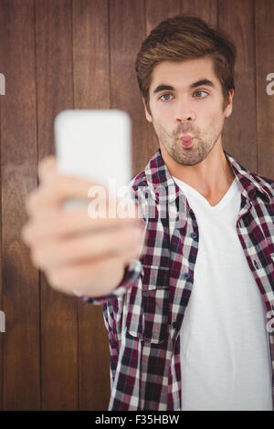 Uomo che fa faccia tenendo selfie Foto Stock