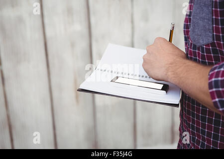 Immagine ritagliata dell uomo con lo smartphone la scrittura sul libro Foto Stock