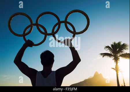 RIO DE JANEIRO, Brasile - 05 Marzo 2015: atleta detiene anelli olimpici in silhouette al tramonto sulla spiaggia di Ipanema. Foto Stock