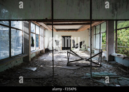 Edificio abbandonato interni. Hall prospettiva con sporcizia sul pavimento e finestre rotte Foto Stock