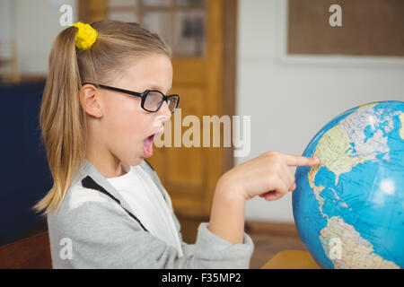 Stupito allievo puntando sul globo terrestre in una classe Foto Stock